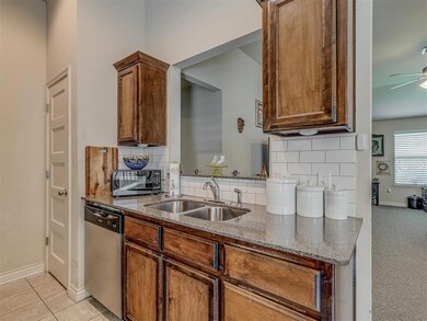 Kitchen featuring stainless steel dishwasher, black microwave, dark stone counters, and backsplash