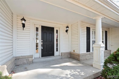 Doorway to property featuring covered porch and stone siding