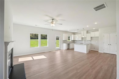 Unfurnished living room with a ceiling fan, recessed lighting, light wood finished floors, and a glass covered fireplace