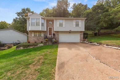 Split foyer home with brick siding, a front lawn, a chimney, concrete driveway, and a garage