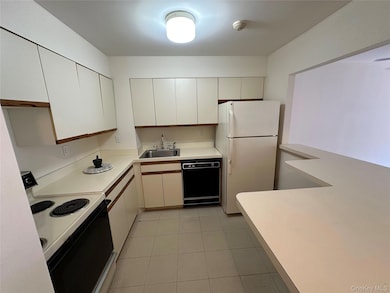 Kitchen featuring white appliances, light countertops, light tile patterned floors, and white cabinetry