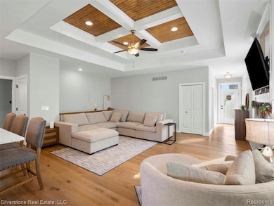 Living area with coffered ceiling, light wood-type flooring, recessed lighting, a wood ceiling with exposed beams, and a ceiling fan