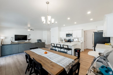 Dining room with a chandelier, ceiling fan, light wood-style floors, and recessed lighting