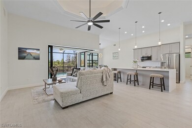 Living room with a tray ceiling, light hardwood / wood-style floors, ceiling fan, and a high ceiling