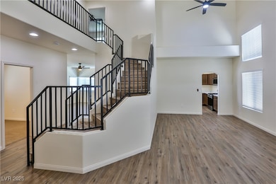 Stairway with a ceiling fan, a towering ceiling, a