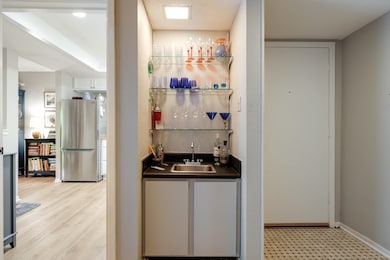 Indoor wet bar with freestanding refrigerator, baseboards, and light flooring