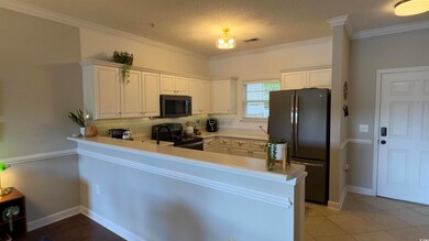 Kitchen featuring white cabinetry, backsplash, black appliances, and ornamental molding