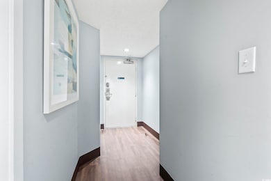 Corridor with a textured ceiling, baseboards, and 