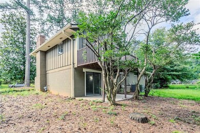 Rear view of house featuring board and batten siding, a chimney, a patio, and a wooden deck
