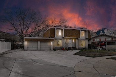 View of front of house with concrete driveway, brick siding, a garage, a mountain view, and mansard roof