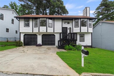 Split foyer home featuring a front lawn, an attached garage, a chimney, and driveway