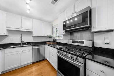 Kitchen with sink, white cabinetry, stainless stee