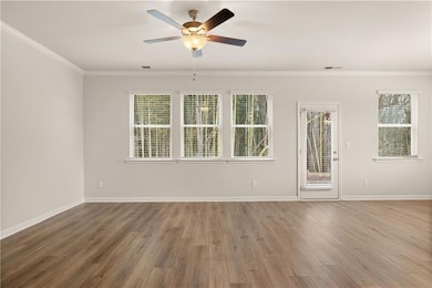 Unfurnished room with ornamental molding, wood finished floors, and a ceiling fan