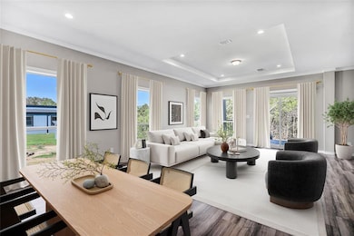 Dining space featuring a tray ceiling, ornamental molding, wood finished floors, and recessed lighting
