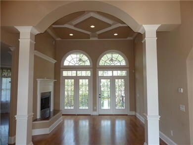The formal living room features windows with transoms, French doors leading to the deck, gorgeous hardwood floors, custom molding, coffered ceilings, and a double sided fireplace.   