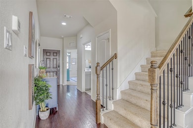 Foyer with dark wood-style floors, stairs, and re