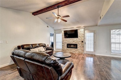 Living area with a ceiling fan, dark wood-type flooring, and a fireplace