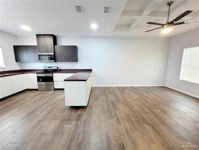 Kitchen with visible vents, open floor plan, dark countertops, appliances with stainless steel finishes, and light wood finished floors