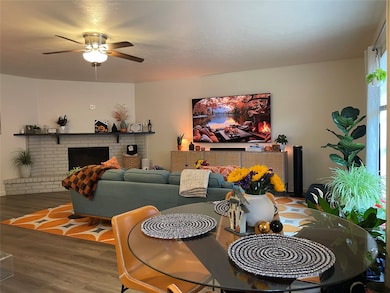 Dining area with wood finished floors, a fireplace, and ceiling fan