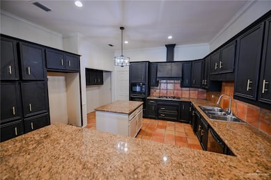 Kitchen featuring backsplash, dark cabinets, light stone counters, ornamental molding, and light tile patterned flooring