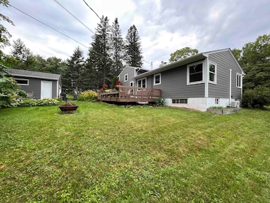 View of grassy yard with an outdoor fire pit and a deck