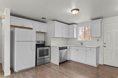 Kitchen featuring stainless steel appliances, light countertops, wood finished floors, and white cabinets