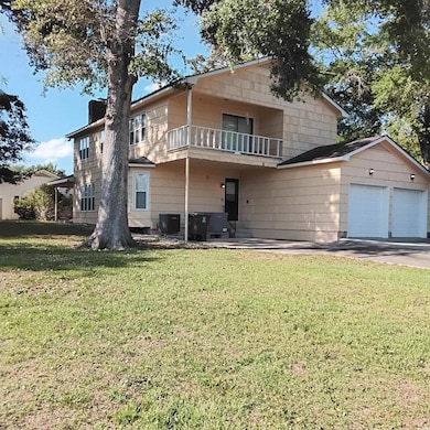 Rear view of house with a balcony, a yard, an attached garage, concrete driveway, and cooling unit