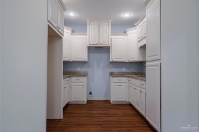 Kitchen with dark hardwood / wood-style floors and white cabinetry