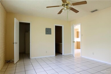Unfurnished bedroom with ensuite bath, ceiling fan, a walk in closet, and light tile patterned floors