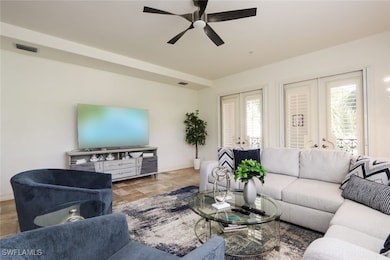 Living room featuring french doors, a ceiling fan,