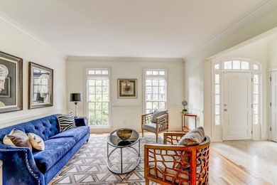 Living area with crown molding, plenty of natural light, a wainscoted wall, and light tile patterned floors