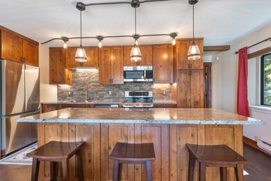 Kitchen with decorative backsplash, brown cabinetry, appliances with stainless steel finishes, and a breakfast bar