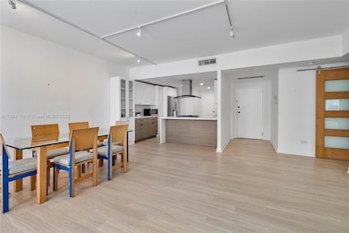 View from the balcony area into the space showing open floorplan, front entry and kitchen area.