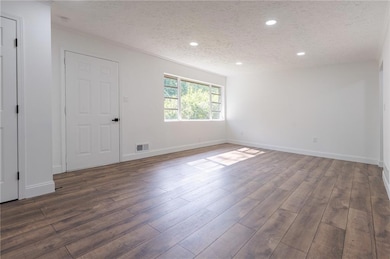 Unfurnished room with a textured ceiling, dark wood-type flooring, recessed lighting, and baseboards