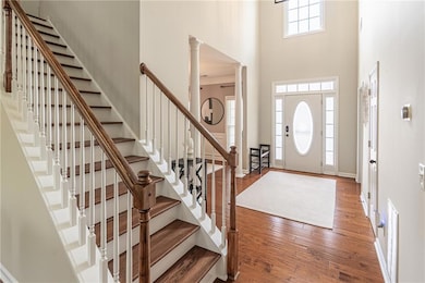 Entryway featuring a towering ceiling, wood finished floors, stairway, and decorative columns