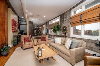 Living area with light wood-style floors, a chandelier, recessed lighting, and brick wall