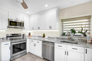 Kitchen with a sink, light stone counters, applian