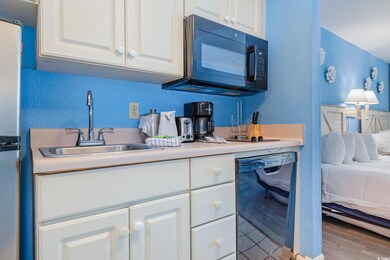 Kitchen with white cabinets, a textured wall, a si