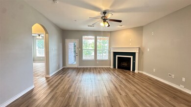 Unfurnished living room featuring ceiling fan, arched walkways, dark wood finished floors, and a fireplace