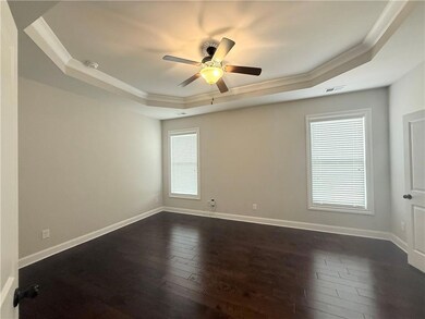 Unfurnished room with a tray ceiling, ornamental molding, dark wood finished floors, ceiling fan, and a smoke detector