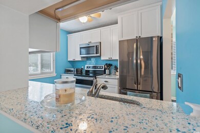 Kitchen with appliances with stainless steel finishes, ceiling fan, tasteful backsplash, white cabinets, and light stone counters