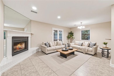 Tiled living area with a warm lit fireplace, plenty of natural light, recessed lighting, a chandelier, and french doors
