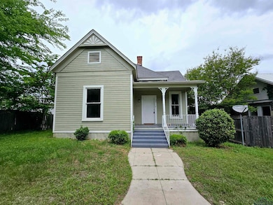 Victorian-style house featuring a porch, a chimney