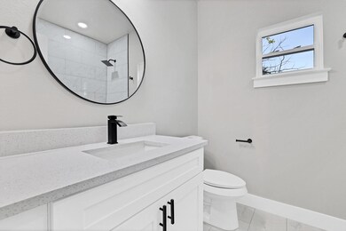 Bathroom featuring a tile shower, vanity, toilet, 