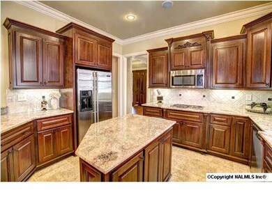 Custom cabinetry, center island with cabinets and power, granite countertops and tumbled stone backsplash with accent tiles are just a few of the features.