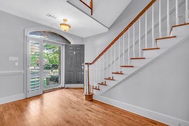 Foyer entrance featuring light wood finished floors, stairway, and crown molding