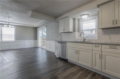 Kitchen featuring dishwasher, dark wood-type flooring, light stone countertops, plenty of natural light, and a textured ceiling