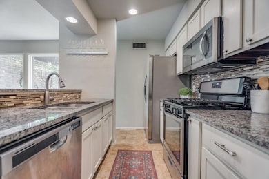 Kitchen featuring white cabinetry, light stone cou