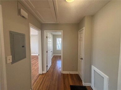 Corridor with attic access, dark wood-type flooring, a textured ceiling, electric panel, and baseboards