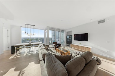 Living area with floor to ceiling windows, a chandelier, and wood finished floors